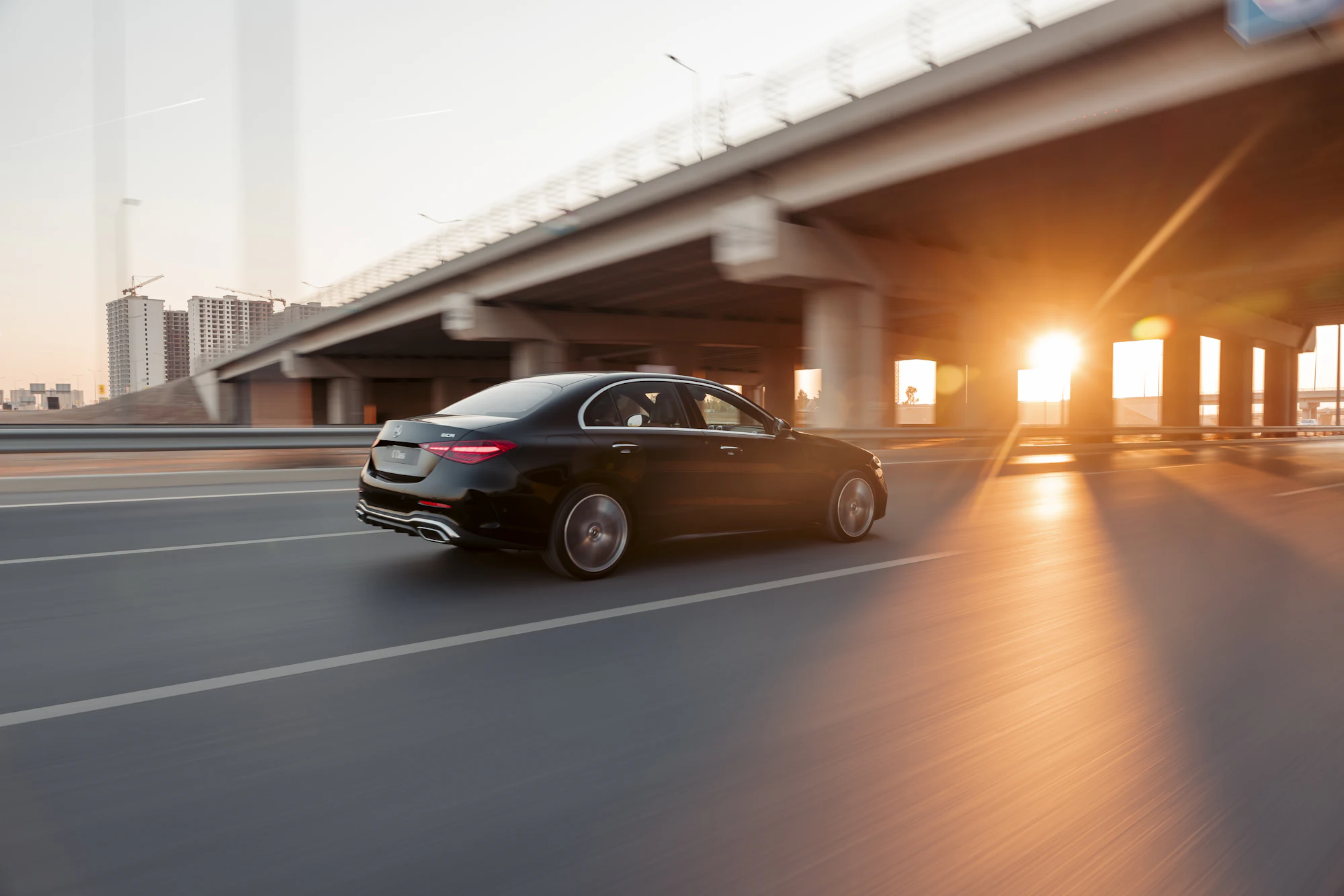 Black sedan on a highway at sunset