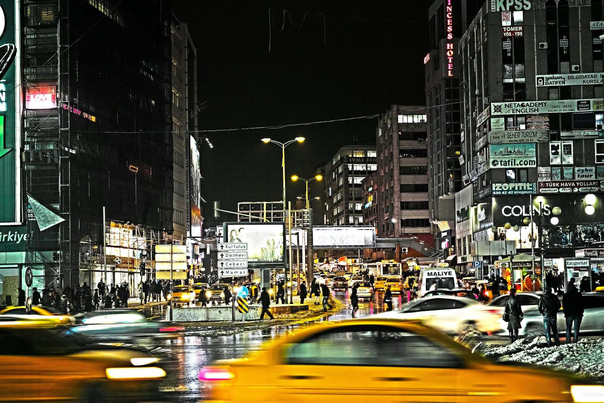 An Ankara city street at night with taxis and lit shop signs