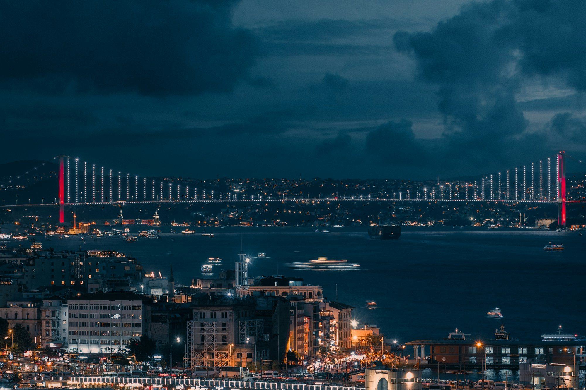 The Bosphorus Bridge lit up red at dusk over Istanbul