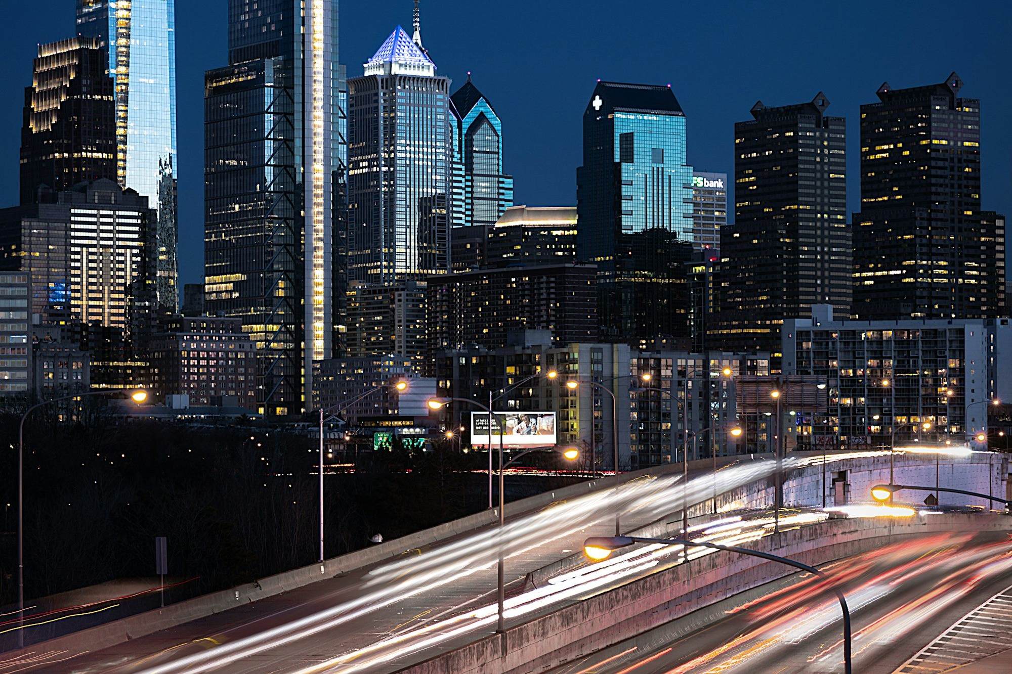 Philadelphia's skyline at night with light trails on the expressway