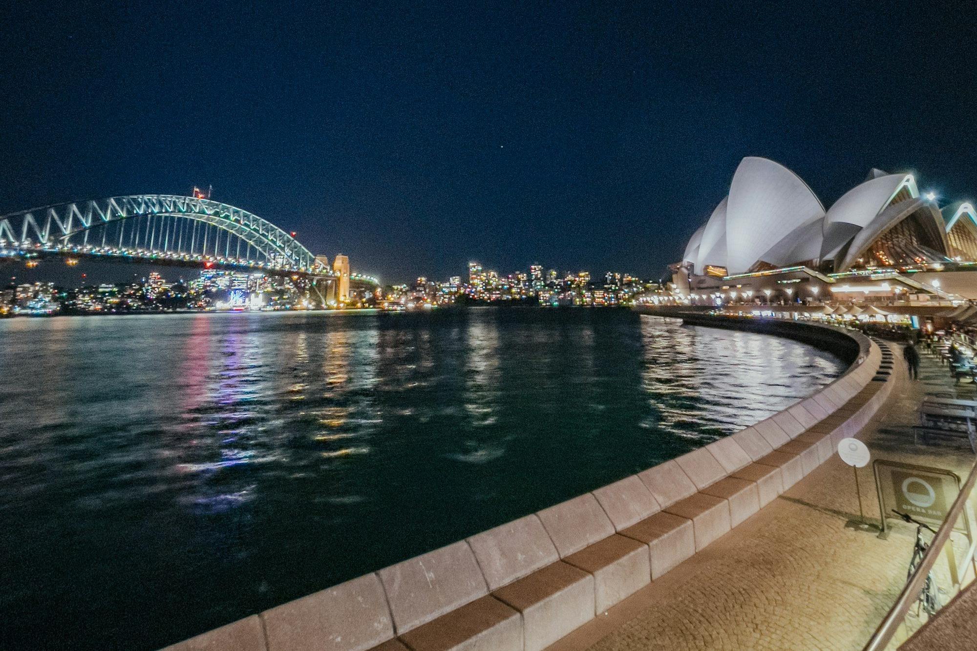 Sydney Opera House and the Harbour Bridge lit up across the harbour at night
