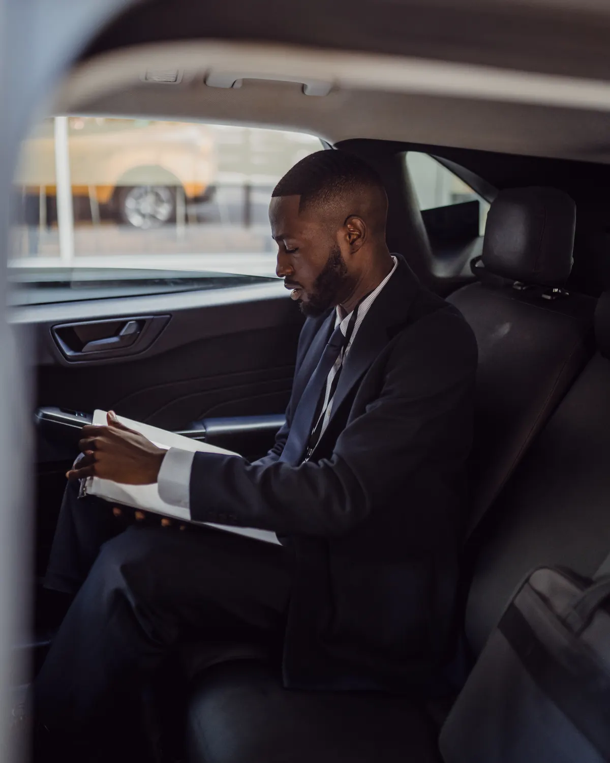 Agent Contract 1 Executive reviewing documents in the rear seat of a chauffeured car