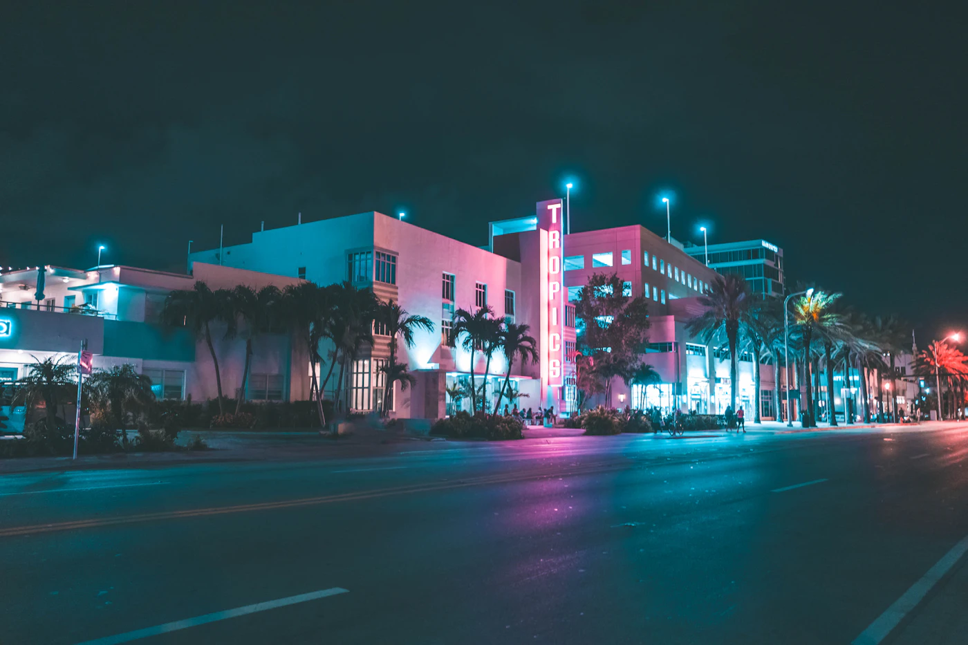 Neon-lit art deco hotel on a palm-lined Miami street at night
